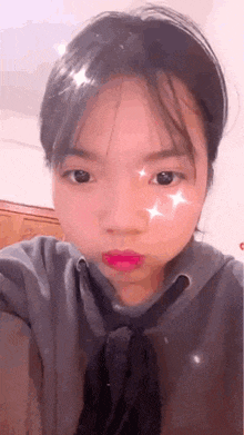 a young girl wearing a hoodie and tie is taking a selfie with a star on her face .