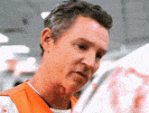 a man wearing an orange vest is looking down at something