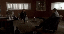 a man and a woman are sitting in chairs in a living room with a glass coffee table .