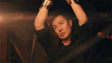 a man with long hair is wearing a black shirt and silver bracelets on his wrists