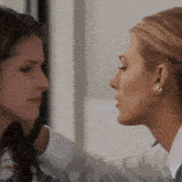 two women are touching each other 's faces and one has a piercing in her ear
