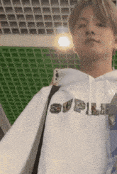 a young man wearing a white hoodie with the word supreme on it