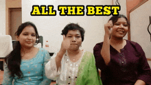 three women are giving a thumbs up in front of a sign that says " all the best "