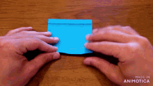 a person is holding a piece of blue paper that says made in animotica on the bottom right