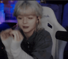 a woman wearing headphones is sitting in a white chair with the word tua on it .