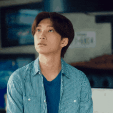 a young man wearing a striped shirt and a blue shirt is looking up