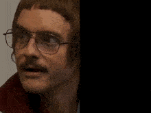 a man with glasses and a mustache is next to a sign that says " i could uhh "