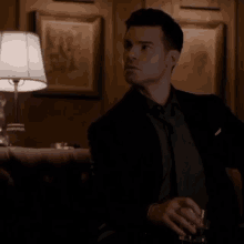 a man in a suit and tie is holding a glass in his hand