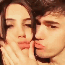 a boy and a girl are kissing each other on the cheek .