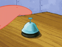 a spongebob bell sits on a wooden table