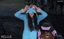 a woman wearing a blue unicorn costume is standing next to a chair