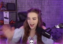 a young woman is sitting in front of a microphone in a purple room .