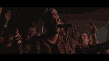 a man singing into a microphone with his hands in the air