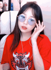 a girl wearing sunglasses and a red shirt has a dragon on her shirt