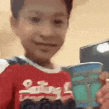 a young boy in a red shirt is holding a toy car