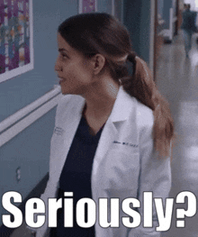 a woman in a lab coat is walking down a hallway and says seriously ?