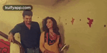 a man and a woman are standing next to each other on a staircase in a room .