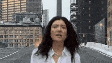 a woman in a white shirt stands in front of a city