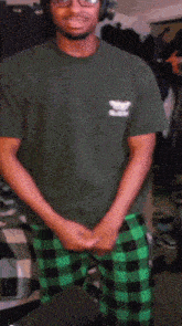 a man in a green shirt and green plaid pants stands in front of a microphone