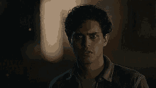 a man with curly hair is looking at the camera in the dark .