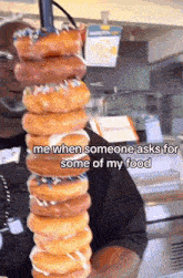 a man is holding a stack of donuts and says me when someone asks for some of my food