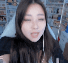 a woman wearing earbuds is sitting in front of a shelf with a sign that says janu on it