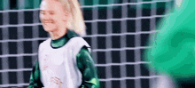 a female soccer player is standing in front of a soccer net .