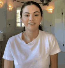 a woman in a white t-shirt is smiling in a room