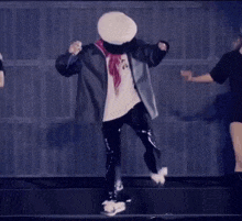 a man wearing a hat and scarf is dancing on stage