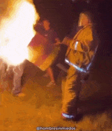 a fireman is standing in front of a fire with the hashtag hombresinmiedos below him