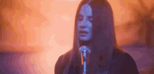 a woman with long hair is singing into a microphone in front of a fire .