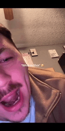 a man with a beard is making a funny face while sitting in a room with a ceiling fan .
