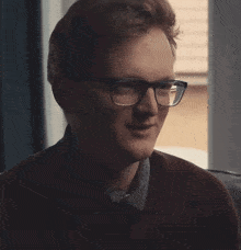 a man with glasses is making a funny face with his mouth open