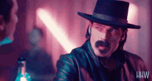 a man wearing a top hat and a leather jacket with the letters hw on his chest