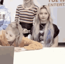 two women are sitting at a table looking at a laptop .
