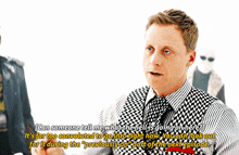 a man in a checkered vest and tie says " can someone tell me what the hell 's going on here ? "