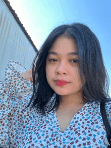 a woman wearing a blue and white floral shirt