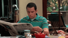 a man sits at a table reading a los angeles register newspaper