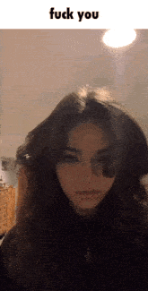 a girl with long hair is standing in front of a light with the words fuck you above her