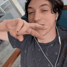 a man wearing headphones and a gray shirt has a red nail polish on his nails .