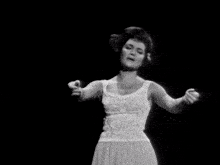 a black and white photo of a woman in a white dress dancing