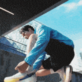 a man wearing a blue jacket and black shorts is tying his shoe
