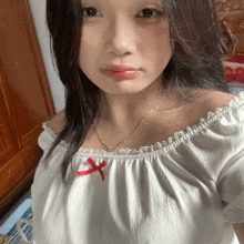 a woman wearing a white off the shoulder top with a red bow on it