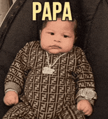 a baby wearing a fendi outfit and a watch is sitting in a stroller