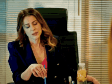 a woman in a blue jacket is sitting at a desk