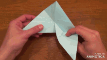 a person is folding a piece of paper with the words made in animatica visible