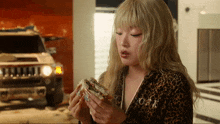 a woman in a leopard print outfit is eating a sandwich with a hummer in the background