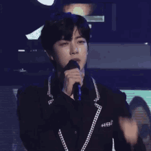 a man in a black suit is holding a microphone in his hand .