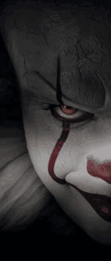 a close up of pennywise the clown 's face with blood coming out of his eyes .