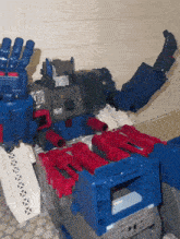 a toy robot with red and blue weapons is laying on a tiled floor